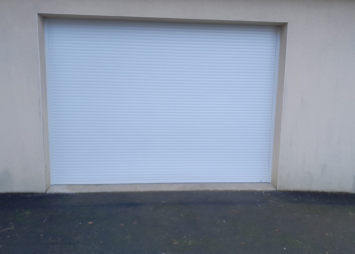 Porte de garage motorisée par Marchand Père et Fils Porte de garage motorisée blanche installée par Marchand Père et Fils pour sécuriser et simplifier l’accès au garage
